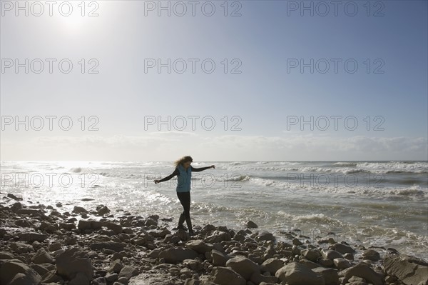 France, Pas-de-Calais, Escalles, Young woman strolling on rocky beach. 
Photo : Jan Scherders