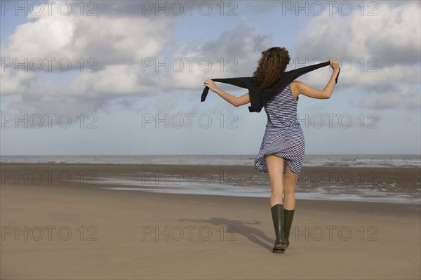 France, Pas-de-Calais, Escalles, Young woman strolling on empty beach. 
Photo : Jan Scherders