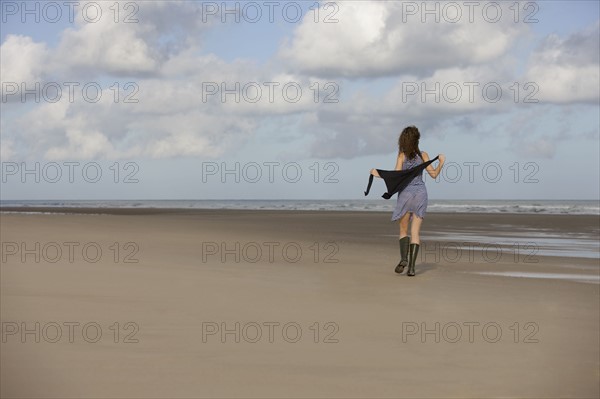 France, Pas-de-Calais, Escalles, Young woman strolling on empty beach. 
Photo : Jan Scherders