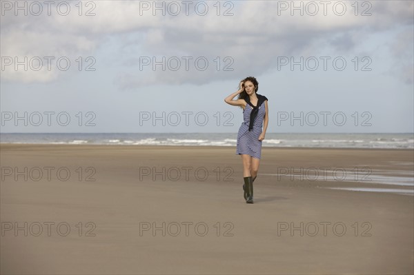 France, Pas-de-Calais, Escalles, Young woman strolling on empty beach. 
Photo : Jan Scherders