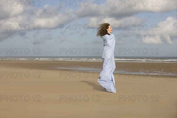 France, Pas-de-Calais, Escalles, Young woman strolling on empty beach. 
Photo: Jan Scherders