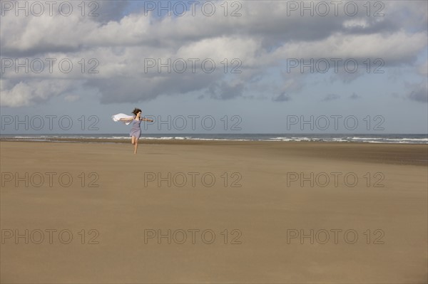 France, Pas-de-Calais, Escalles, Young woman strolling on empty beach. 
Photo : Jan Scherders