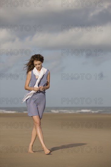 France, Pas-de-Calais, Escalles, Young woman strolling on empty beach. 
Photo: Jan Scherders