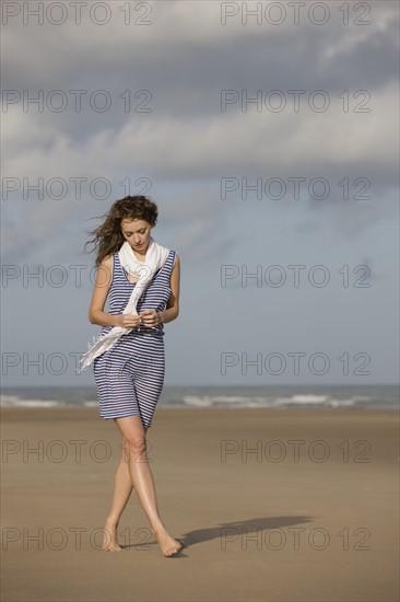 France, Pas-de-Calais, Escalles, Young woman strolling on empty beach. 
Photo : Jan Scherders