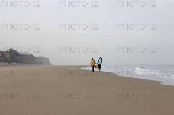 France, Pas-de-Calais, Escalles, Two women strolling on empty beach. 
Photo : Jan Scherders