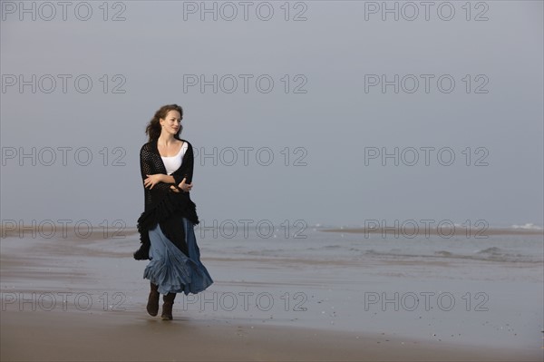 France, Pas-de-Calais, Escalles, Young woman strolling on empty beach. 
Photo : Jan Scherders