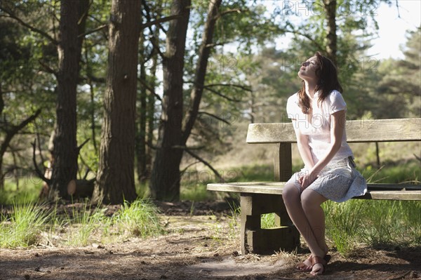 Belgium, Kalmthoutse Heide, Young woman sitting on bench. 
Photo : Jan Scherders