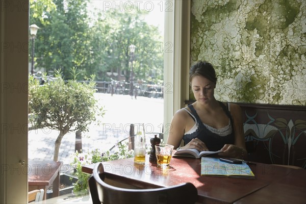 Holland, Amsterdam, Woman sitting with book in cafe window. 
Photo : Jan Scherders