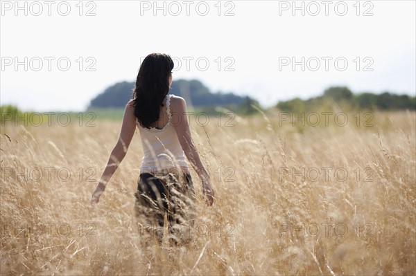 France, Picardie, Albert, Young woman strolling in cornfield. 
Photo: Jan Scherders