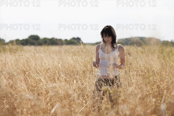 France, Picardie, Albert, Young woman strolling in cornfield. 
Photo : Jan Scherders