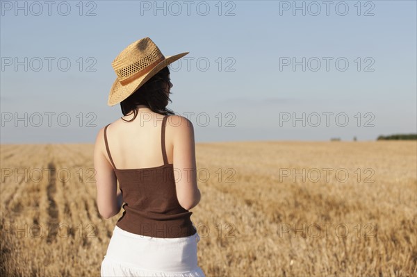 France, Picardie, Albert, Young woman in straw hat looking at country landscape. 
Photo : Jan Scherders