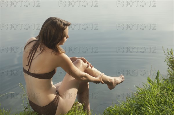 Young woman relaxing on lakeside. 
Photo: Jan Scherders