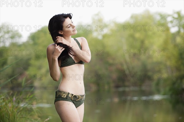 France, Picardie, Albert, Young woman in bikini standing by lake shore. 
Photo : Jan Scherders