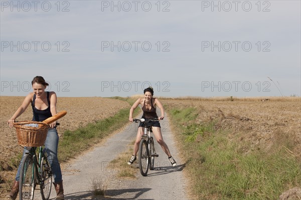 France, Picardie, Albert, Young women cycling on country road. 
Photo: Jan Scherders