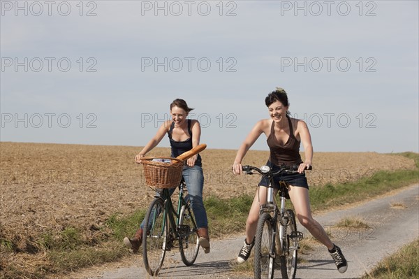 France, Picardie, Albert, Young women on bikes on country road. 
Photo : Jan Scherders