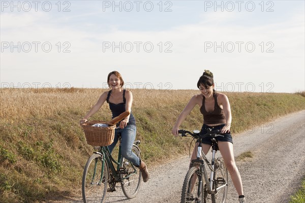 France, Picardie, Albert, Young women on bikes on country road. 
Photo : Jan Scherders