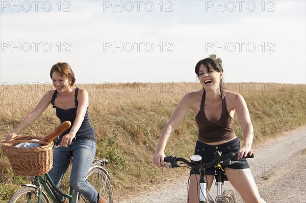 France, Picardie, Albert, Young women on bikes on country road. 
Photo: Jan Scherders