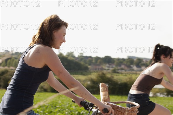 France, Picardie, Albert, Young women on bikes on country road. 
Photo : Jan Scherders