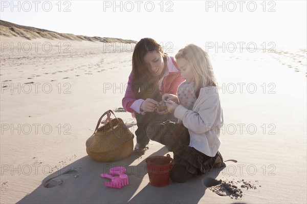 Mother with daughter collecting shells on beach. 
Photo : Jan Scherders