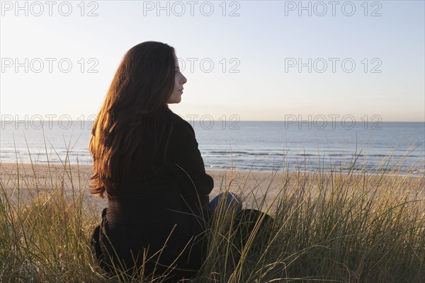 Netherlands, Zeeland, Haamstede, Woman relaxing on sand dune. 
Photo: Jan Scherders