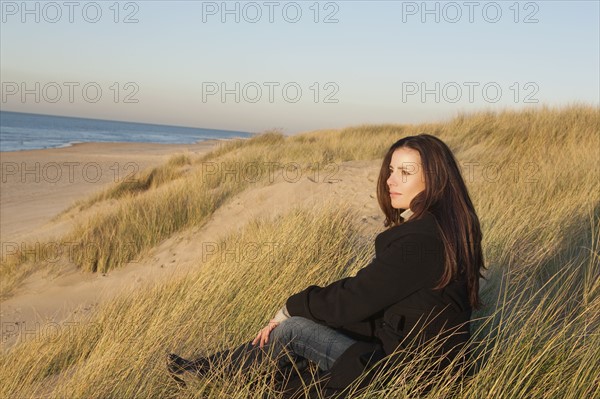 Netherlands, Zeeland, Haamstede, Woman relaxing on sand dune. 
Photo: Jan Scherders