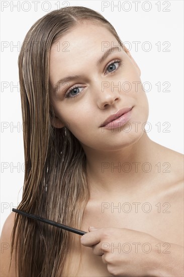 Portrait of young woman with wet hair and comb. 
Photo: Jan Scherders