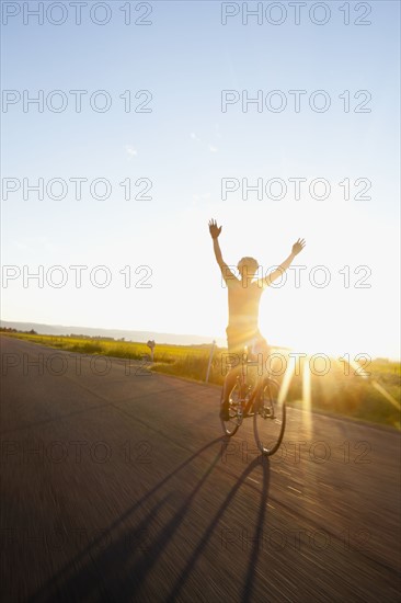Silhouette of cyclist holding arms up. 
Photo : Noah Clayton