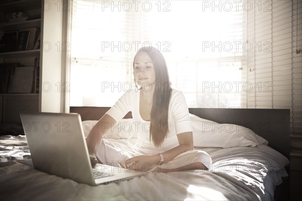 Woman using laptop in bed. 
Photo : King Lawrence