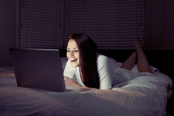 Woman using laptop in bed. 
Photo: King Lawrence