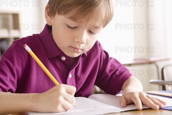 Schoolboy writing in notebook. 
Photo : Rob Lewine