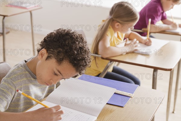 Schoolchildren focused on writing in classroom. 
Photo : Rob Lewine