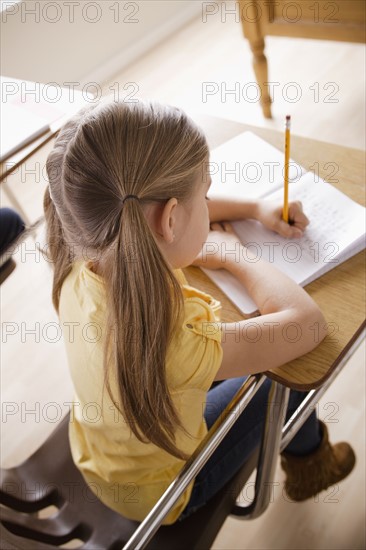 Schoolgirl focused on writing in classroom. 
Photo : Rob Lewine
