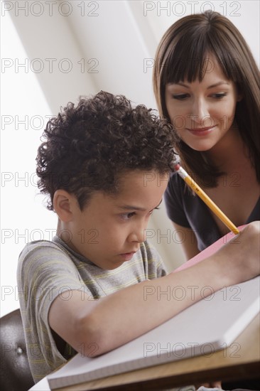 Pupil writing together with teacher. 
Photo : Rob Lewine