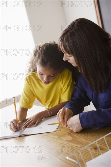 Schoolgirl writing with teacher in classroom. 
Photo : Rob Lewine