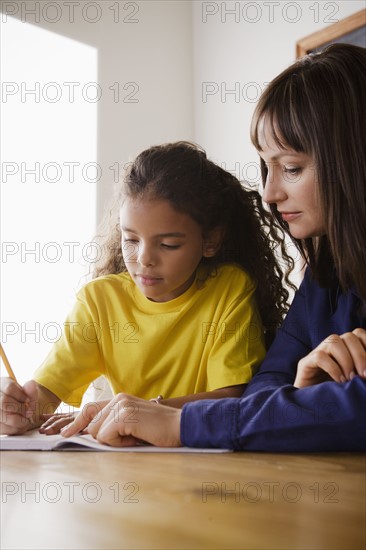 Schoolgirl writing with teacher in classroom. 
Photo: Rob Lewine