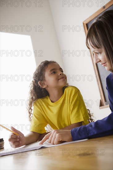 Schoolgirl writing with teacher in classroom. 
Photo : Rob Lewine