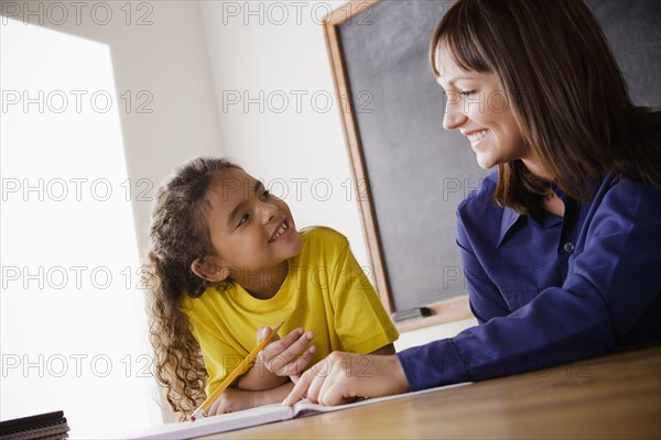 Schoolgirl writing with teacher in classroom. 
Photo : Rob Lewine