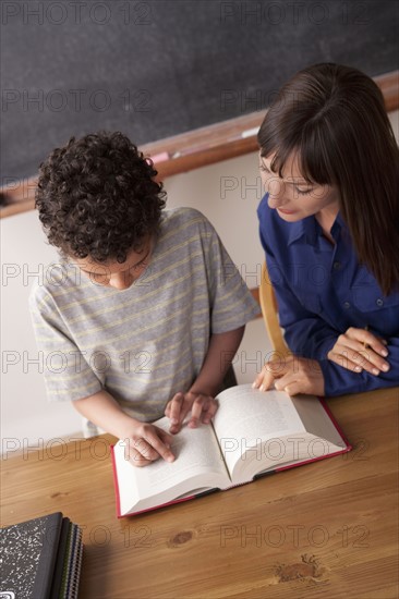Schoolboy reading with teacher in classroom. 
Photo : Rob Lewine