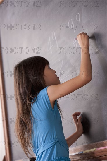 Schoolgirl writing on blackboard. 
Photo: Rob Lewine