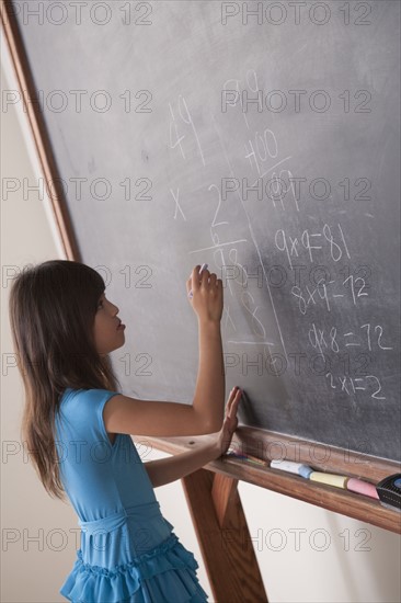 Schoolgirl writing on blackboard. 
Photo: Rob Lewine