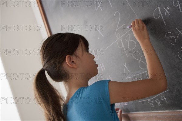 Schoolgirl writing on blackboard. 
Photo: Rob Lewine