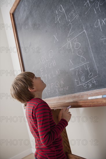 Schoolboy writing on blackboard. 
Photo: Rob Lewine