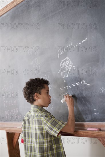 Schoolboy writing on blackboard. 
Photo : Rob Lewine