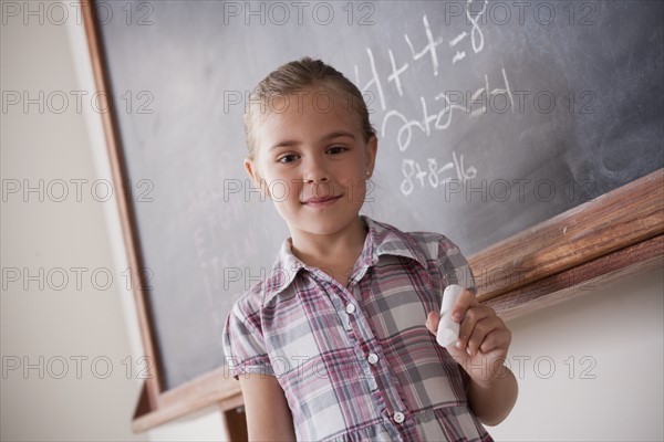 Portrait of schoolgirl holding chalk. 
Photo : Rob Lewine