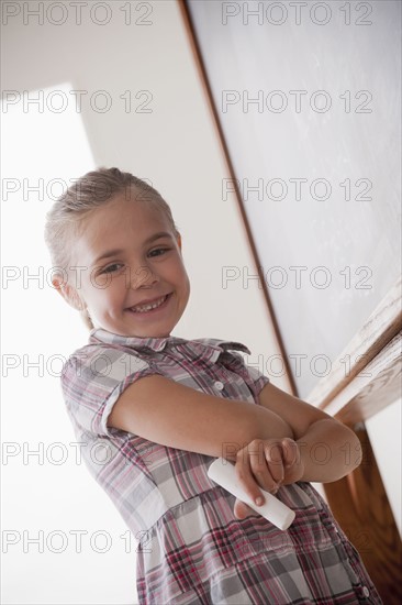 Portrait of schoolgirl holding chalk. 
Photo : Rob Lewine