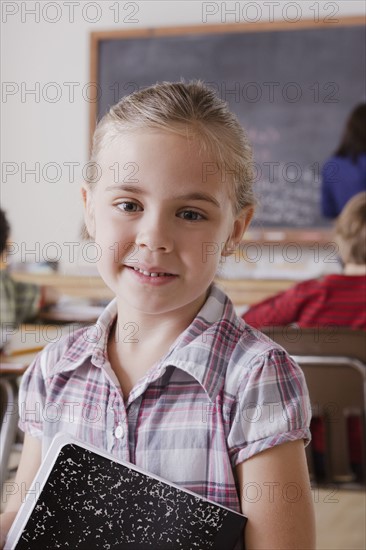 Portrait of schoolgirl holding notebook. 
Photo : Rob Lewine