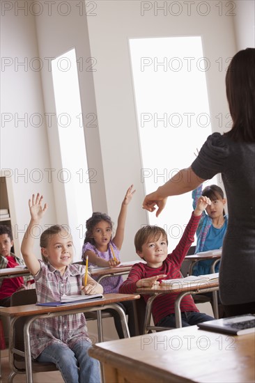 Pupils in classroom raising hands. 
Photo : Rob Lewine