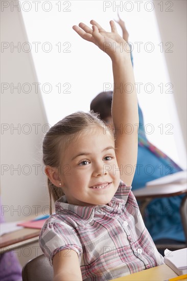 Pupils in classroom raising hands. 
Photo : Rob Lewine