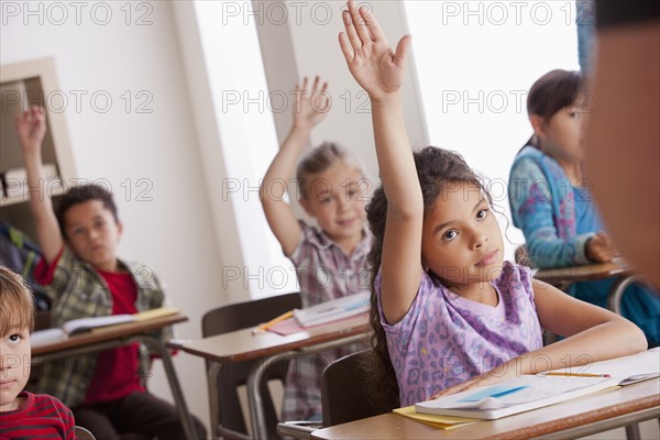 Pupils in classroom raising hands. 
Photo : Rob Lewine