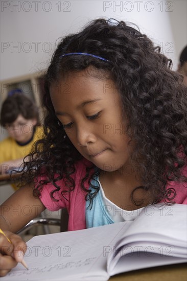 Writing girl (10-11) with boy (10-11) in background. 
Photo : Rob Lewine